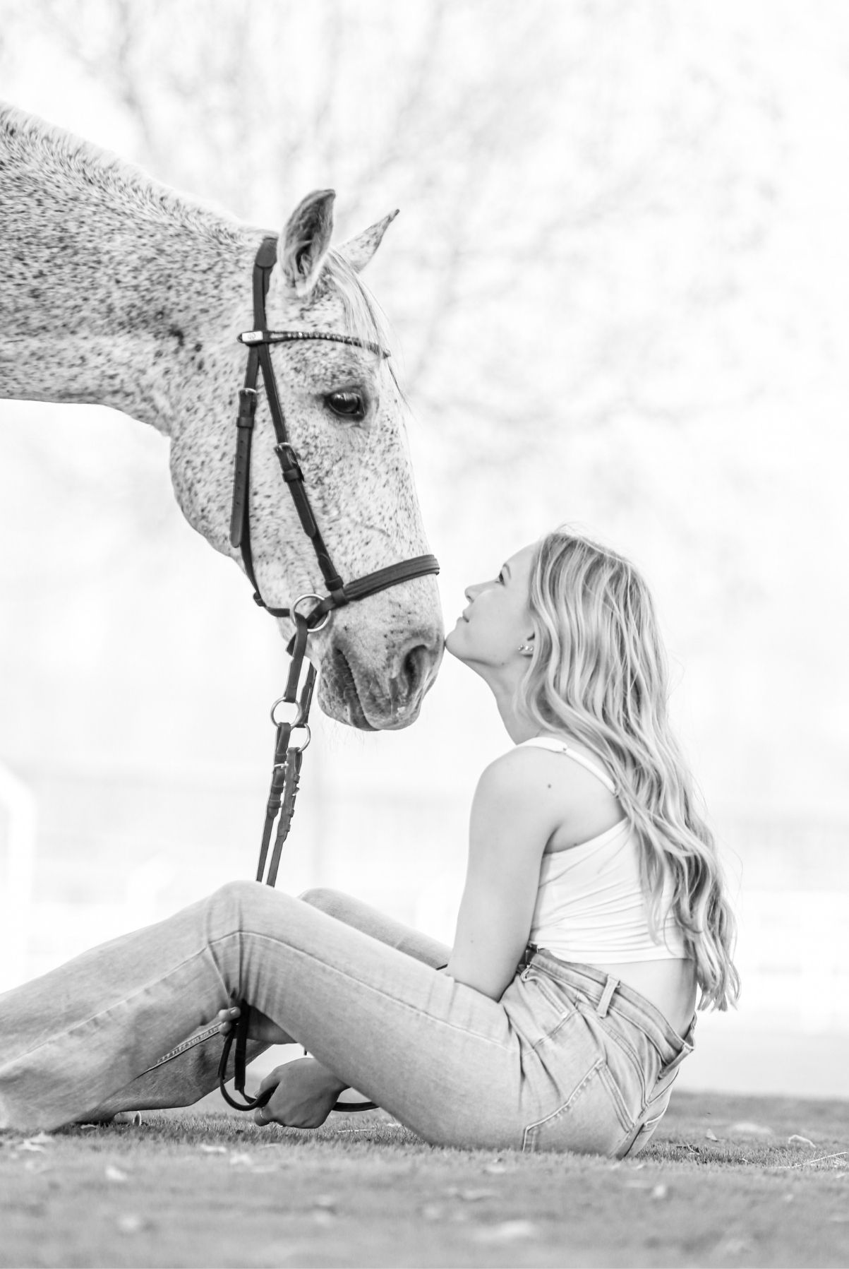 Woman kissing a grey horse, in black and white.